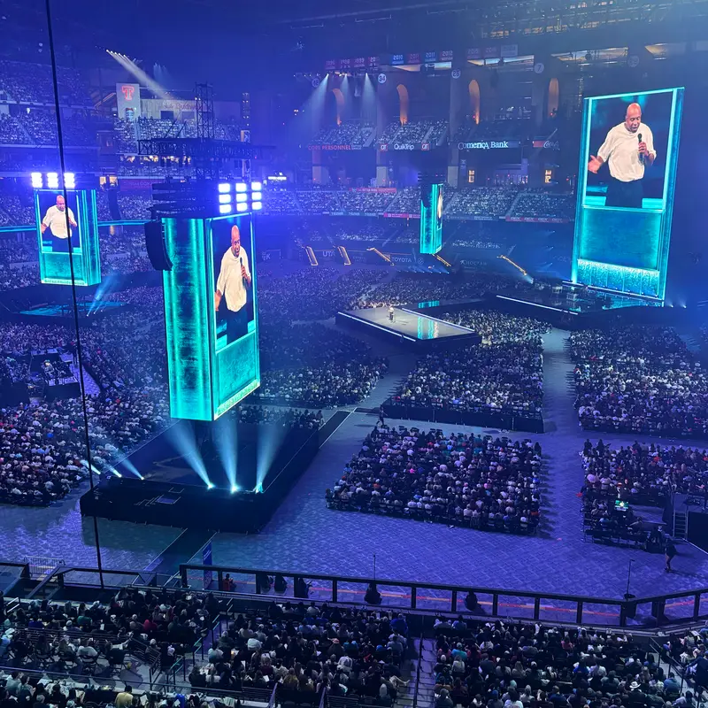 Packed arena at Passion 2026 with the speaker on a center stage